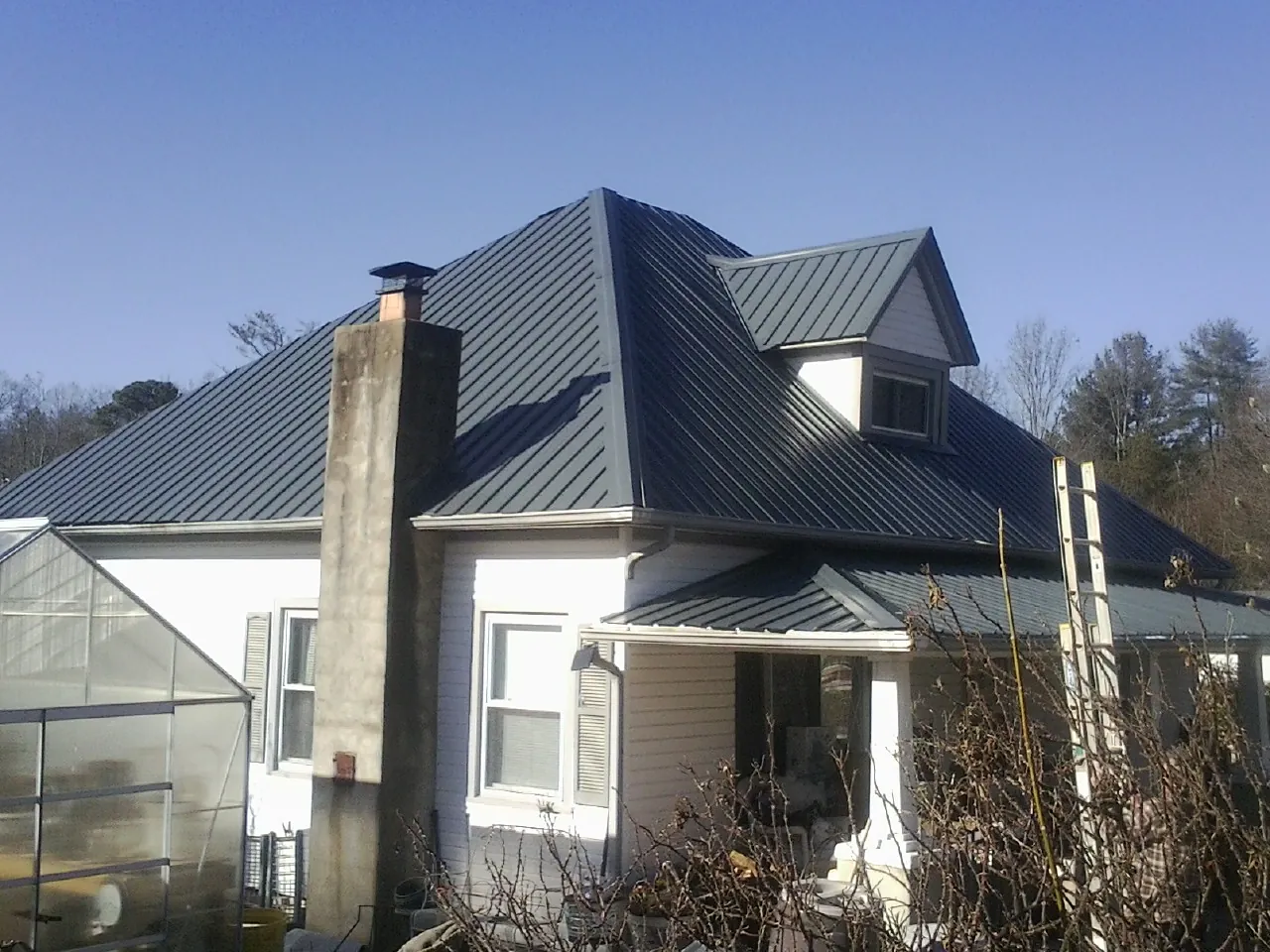 Dark blue standing seam metal roof on a white farmhouse with dormer — Slate & Tile Roof Repair by Roofing Brothers in Mount Shasta