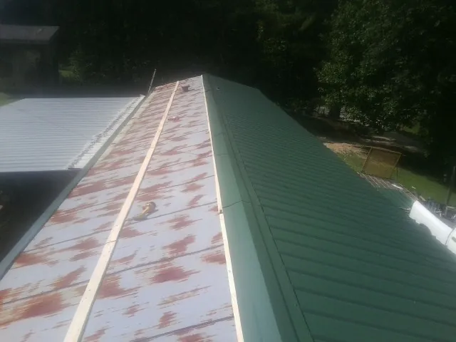 Old rusted panels beside newly installed green metal roofing — Wind Damage Roof Repair by Roofing Brothers in Mount Shasta