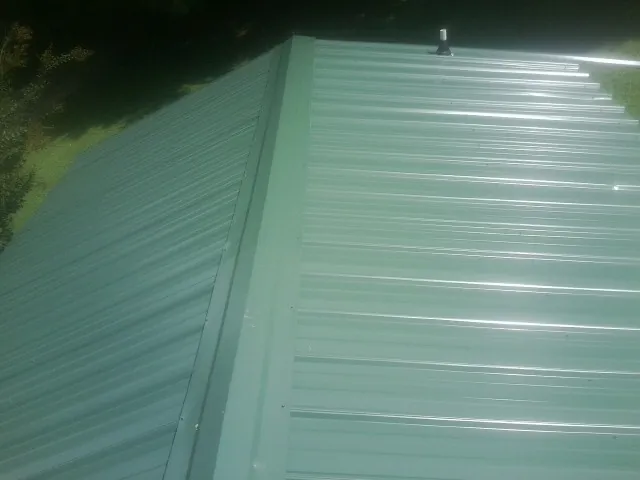 New green metal panels meeting at the ridge of a roof — Flat Roof Repair work by our crew in Mount Shasta