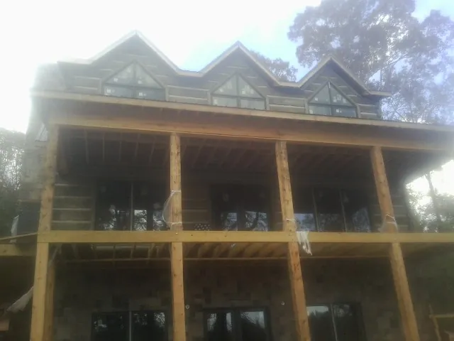 Dormers and porch framing on a large log home under construction — Roof Coating work by our crew in Mount Shasta