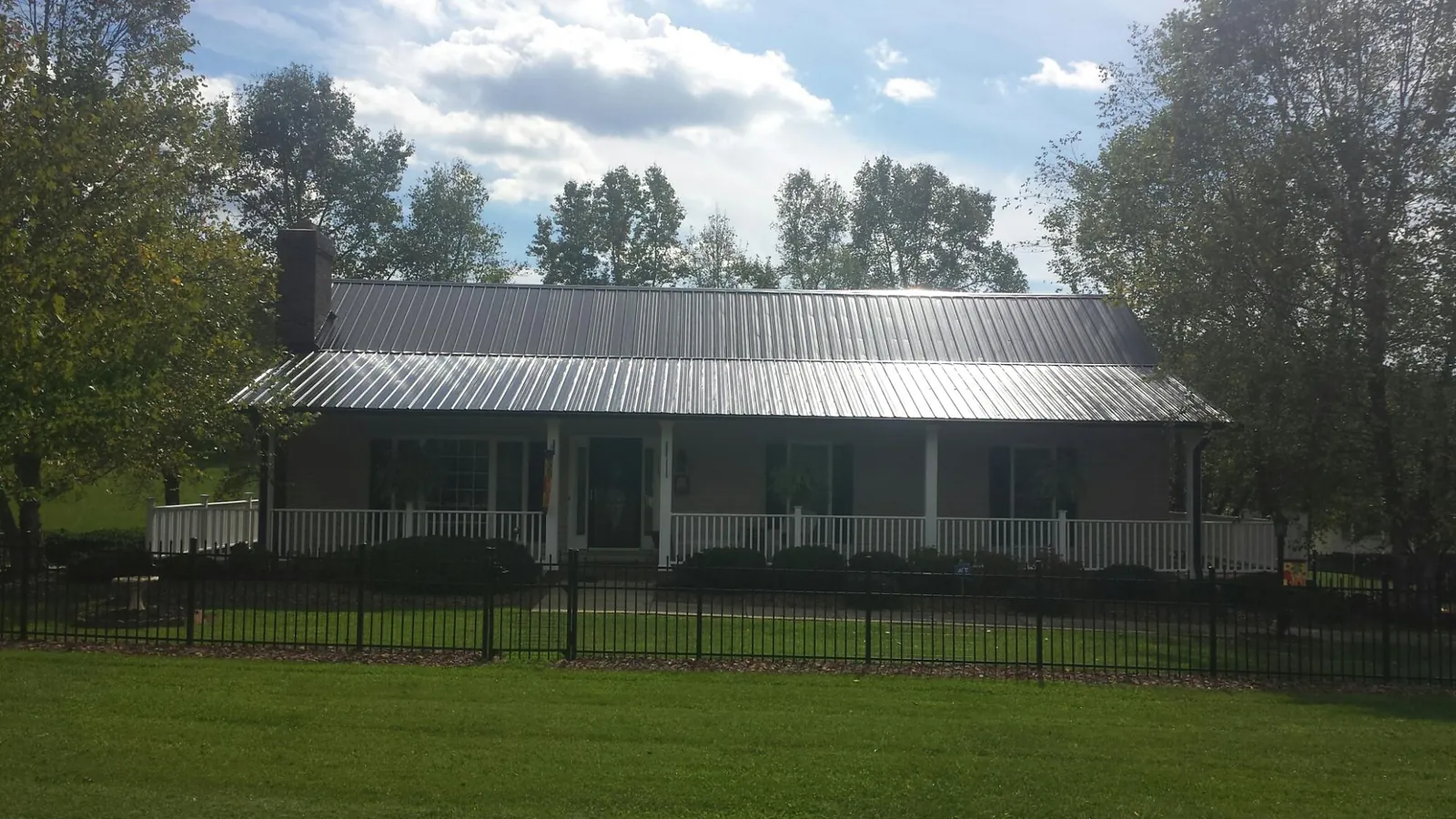 Gray metal roof on a brick ranch with a full width front porch — Gutter Guard Installation work by our crew in Mount Shasta