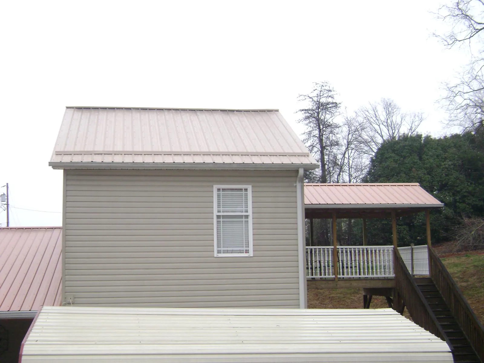 Tan metal roofs on a two story addition and attached porch, from a Roof Replacement job in Mount Shasta