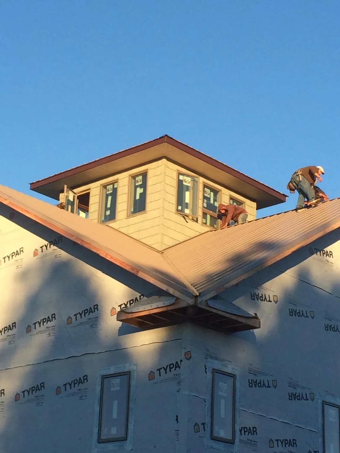 Roofers working around a rooftop cupola on a new metal roof at sunset — Roof Waterproofing in Mount Shasta by Roofing Brothers